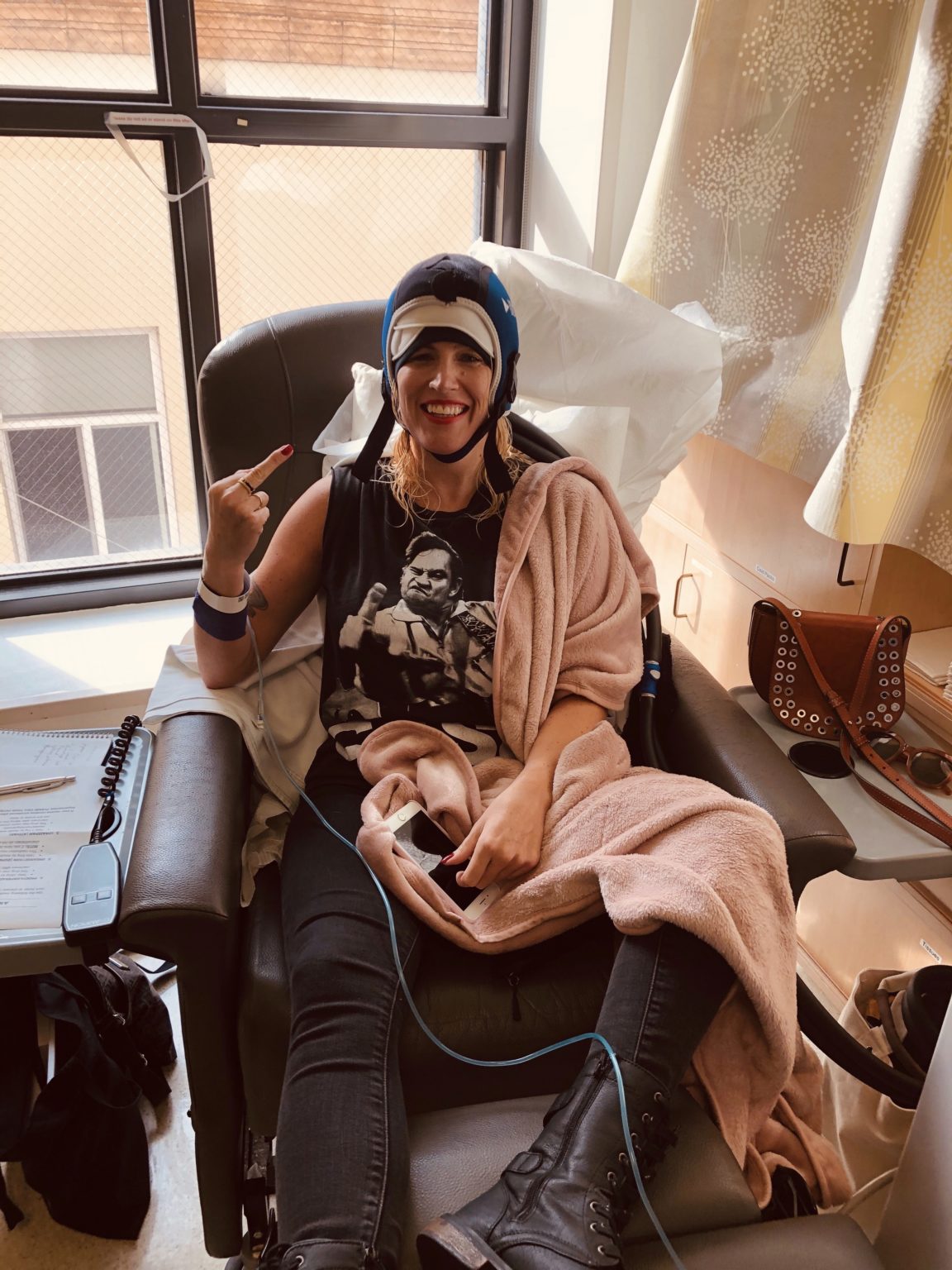 Marisa Sullivan Smiles In A Chemo Chair As She Holds Up Her Middle Finger To Cancer